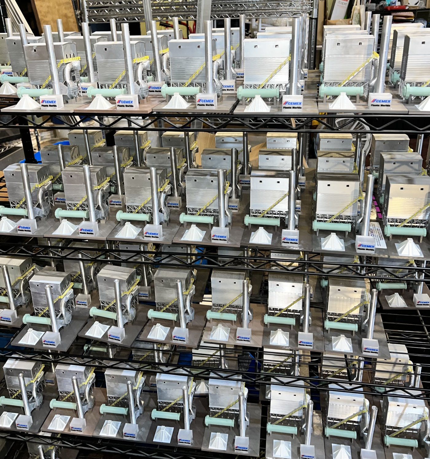 Dozens of custom-printed industrial site models for CEMEX, arranged on shop shelving